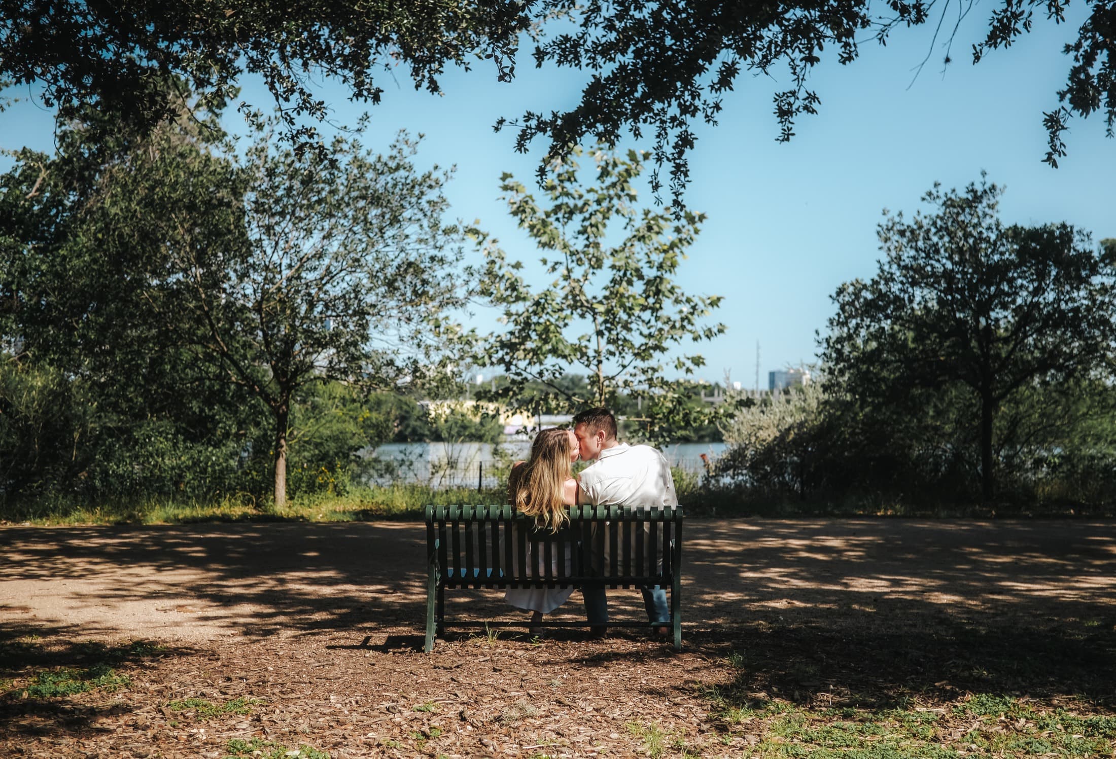 Jake and Ellen sharing a kiss on a park bench overlooking the water